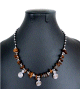 Collier artisanal marocain avec pierres marron foncé, agrémenté de petites breloques tourbillon en métal argenté Collier artisanal marocain avec pierres marron fonce, agremente de petites breloques tourbillon en metal argente