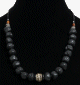 Collier ethnique artisanal imitation boules noires difformes, separees de perles noires avec des perles en bois, en metal et une boules en metal au milieu