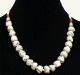 Collier ethnique artisanal imitation pierres blanches separees de petites perles blanches et compose d'autre perles blanches, en bois et en metal