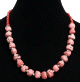 Collier ethnique artisanal imitation pierres de corail separees de perles en metal et compose de perles rouges