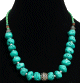 Collier ethnique artisanal imitation pierres difformes turquoises separees de perles en metal avec une boule en metal et des perles vertes